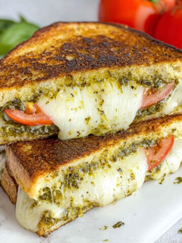Homemade pesto grilled cheese sandwich on a white kitchen counter, shot from above with melted cheese oozing out.