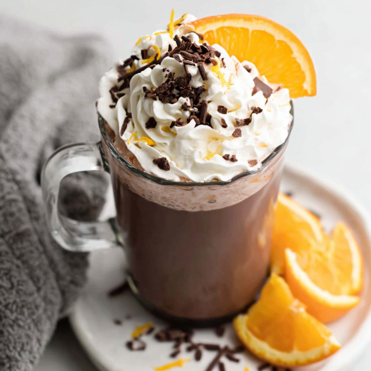 Overhead shot of a homemade orange hot chocolate with whipped cream and orange zest on a white kitchen counter.