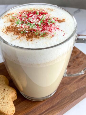 Homemade sugar cookie latte topped with festive sprinkles on a white kitchen counter.