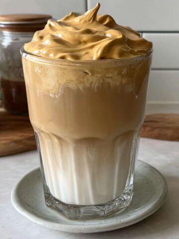 Homemade whipped honey coffee with creamy foam on a white kitchen counter, shot from above.