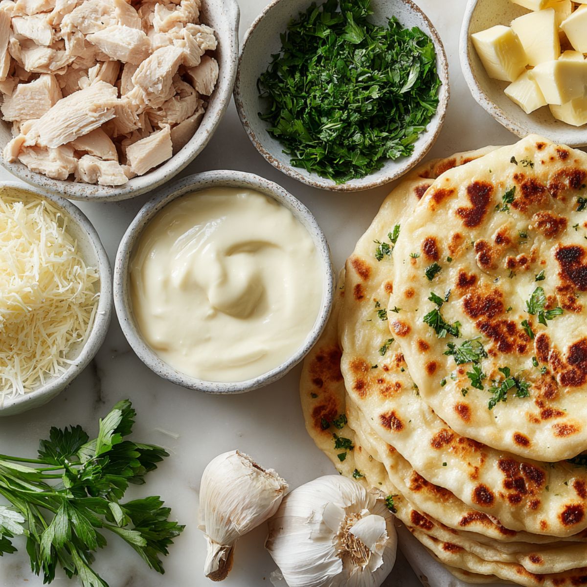Top-down view of homemade chicken alfredo flatbread ingredients arranged casually on a kitchen counter.
