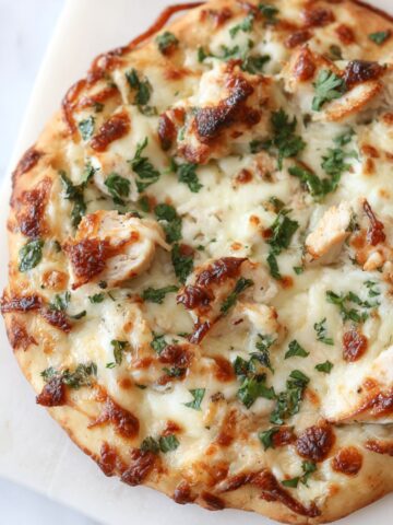 Homemade chicken alfredo flatbread on a white counter