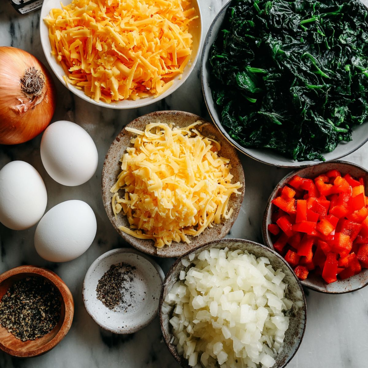 Ingredients for homemade egg spinach bites on a kitchen counter, including eggs, spinach, cheese, and vegetables.