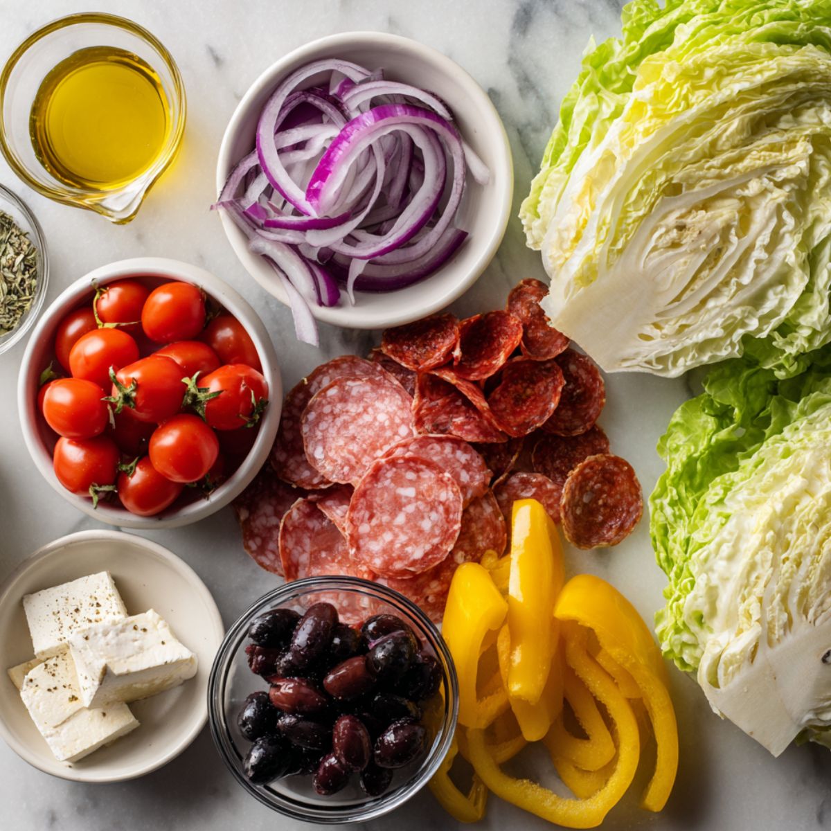 Flat lay of ingredients for Italian grinder salad sandwich on a white kitchen counter, casually arranged for a homemade look.