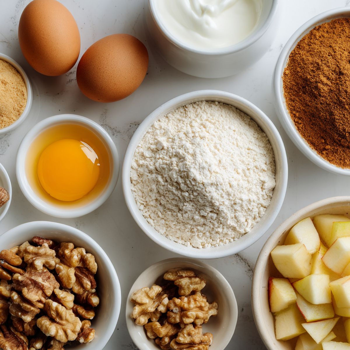 Flat lay of cinnamon protein muffin ingredients on a white kitchen counter.