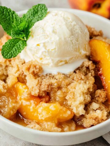 Homemade keto peach cobbler with golden almond flour topping on a white kitchen counter