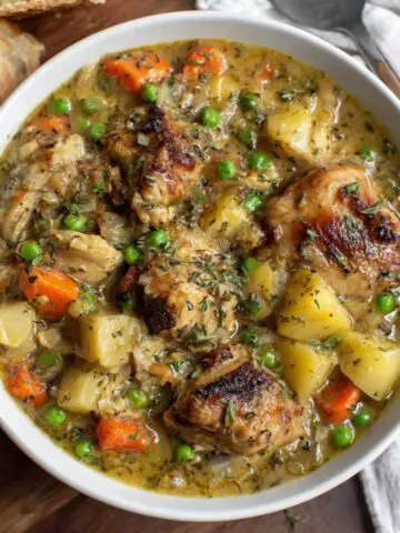 Homemade slow cook chicken stew in a white bowl on a kitchen counter