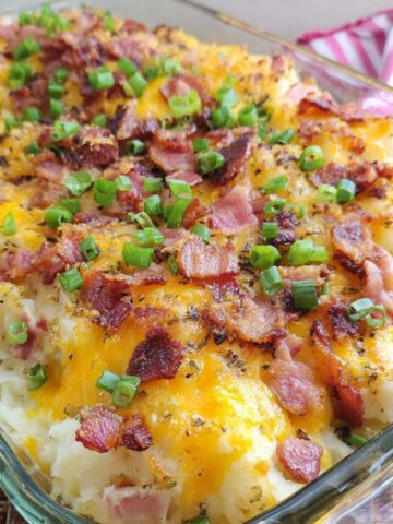 Homemade twice baked potato casserole fresh out of the oven on a kitchen counter with melted cheese and crispy bacon on top.
