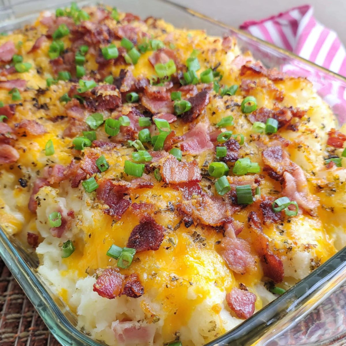 Homemade twice baked potato casserole fresh out of the oven on a kitchen counter with melted cheese and crispy bacon on top.